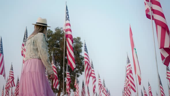 Cinematic Slow Motion of Young Stylish Woman Walking Between Many American Flags