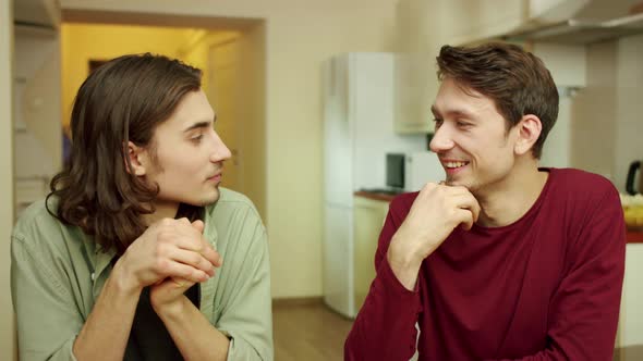 A Young Man is Wiping His Friend's Mouth During Conversation