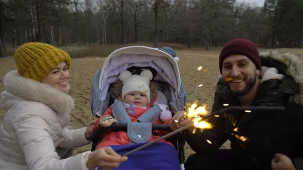 Dad Mom and Little Daughter Celebrate the Holiday with Sparklers on the Street