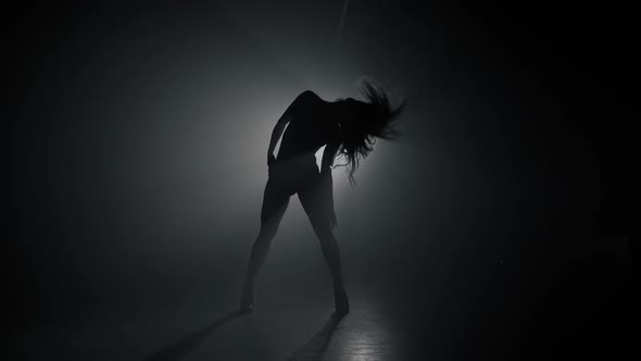 Silhouette of Beautiful Dancer on Smoky Dark Background