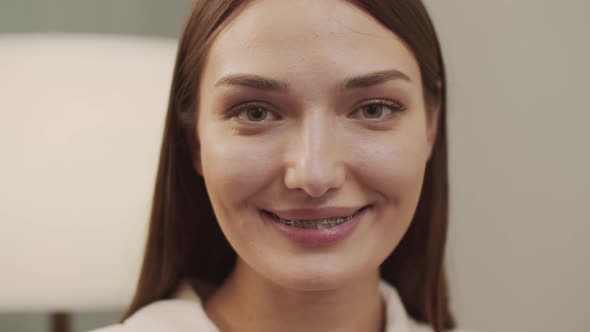 Women with a Charming Smile with Braces Looks Smiles and Talks to the Camera