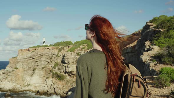 Slow motion shot of redheaded woman walking to lighthouse