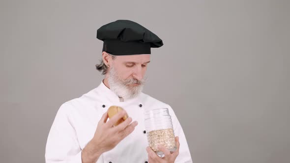 Middle Aged Chef Man Pouring Cereals on Grey Background