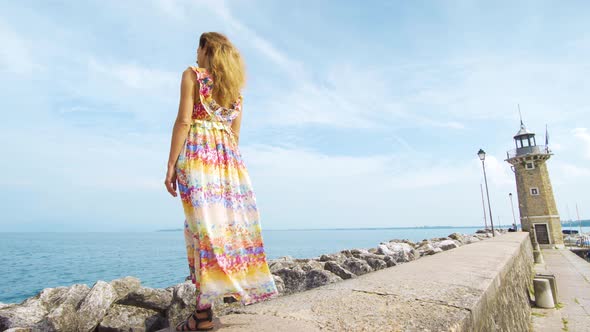 A Girl in a Dress Is Standing on the Ocean Looking at the Lighthouse