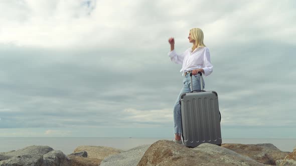 A beautiful woman with a suitcase on the background of the sea