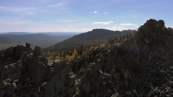 Aerial view of the mountains with rocks and beautiful autumn woods on the slopes