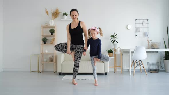 Woman with Little Daughter Doing Yoga Exercises