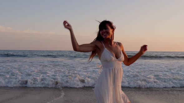 Beautiful woman in a white dress at the beach at sunset