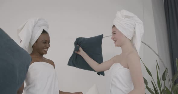 Multiracial Models Fighting with Pillows on Bed