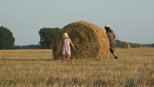 Mother with Daughter Playing with Straw in Field