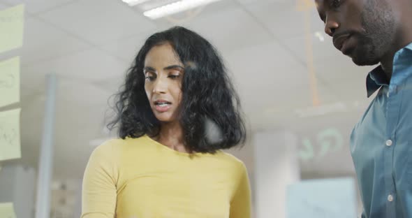 Video of diverse businesswoman and businessman brainstorming in office