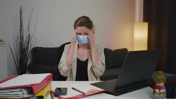 Sick business woman sneezing while working in home office with mask.