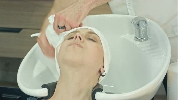 Woman Relaxing After Washing and Treating Hair in Beauty Salon