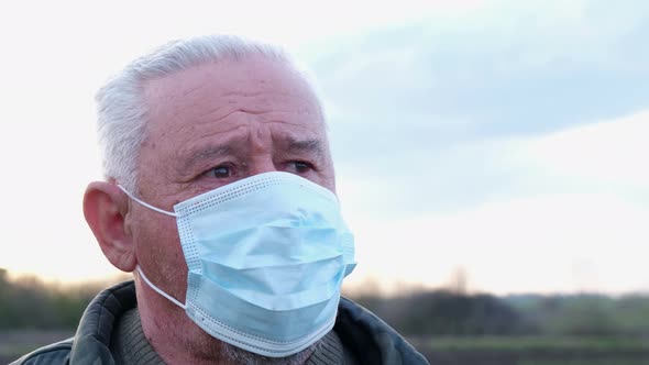 Senior Man Sitting in a Mask in the Yard