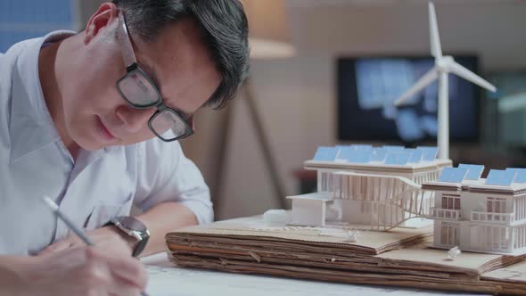 Close Up Of Asian Man Sketch House With Solar Panel On The Blueprint