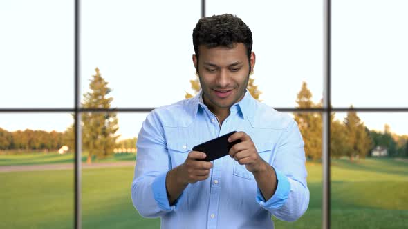 Delighted Man Playing Game on Smartphone.