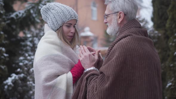 Mature Caucasian Man Coming To Young Girl with Tea Cup Standing Outdoors and Taking Her Hands