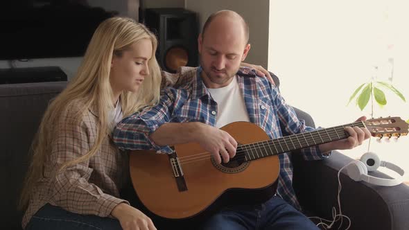 Couple Spending the Time at Home Playing Guitar