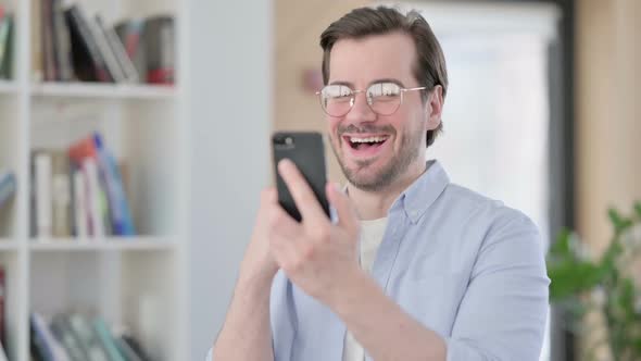 Portrait of Man in Glasses Celebrating on Smartphone