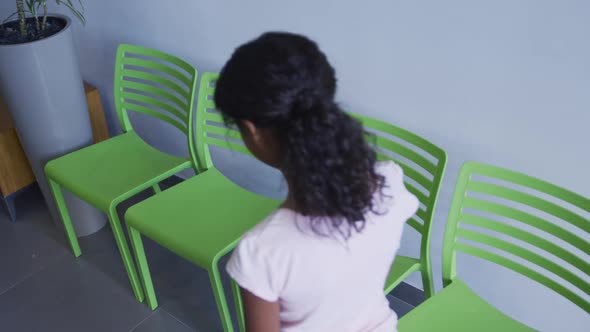 African american girl sitting on a chair in the corridor at hospital