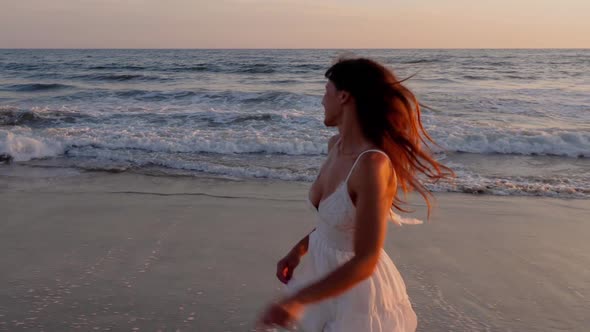 Beautiful woman in a white dress at the beach at sunset