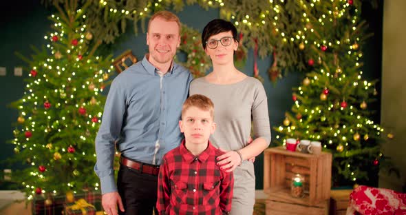 Family is taking a Christmas family picture in front of decorated living room