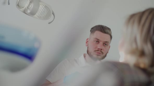 The male dentist explains to the patient the treatment plan at the dental clinic.