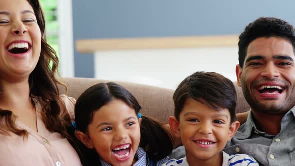 Happy family sitting on sofa and laughing in living room