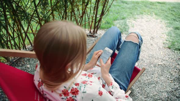 Young Woman Using Smartphone in Plant Gazebo.