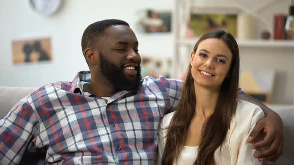 Smiling Multiethnic Couple Hugging and Looking at Camera, Relaxing Together