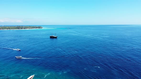 Small boats and a large ship sailing across the surface of beautiful blue waters off the coast of a