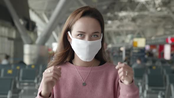 Portrait of Woman Put Off Medical Mask Looking Straight at Camera in Airport Terminal. End of