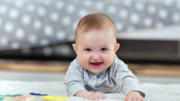 Portrait of Adorable Little Cute Baby Smiling Lying on Fluffy Carpet at Home Looking at Camera