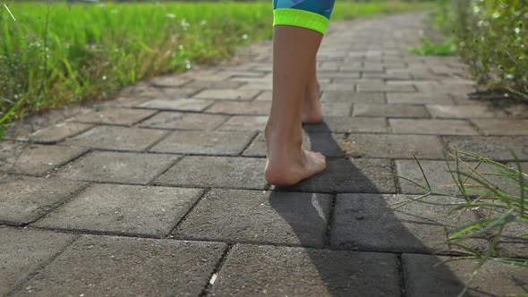 Slowmotion Steadicam Shot of a Young Woman with Yoga Math Walking Through a Beautiful Rice Field