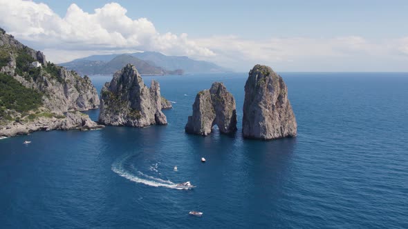 Tourists Boating by the Epic Faraglioni Rocks off Capri Island, Italy - Aerial