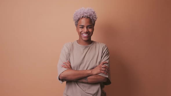 Smiling Millennial African Woman Standing with Folded Arms Over Beige Background