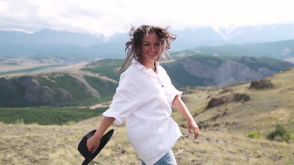 Attractive Brunette in a Hat and White Shirt Is Enjoying Nature in the Mountains. Beautiful Young