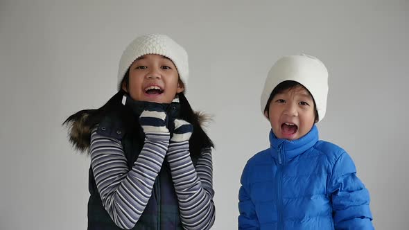 Cute Asian Children In Winter Clothes Is Surprise And So Happy About It On Gray Background