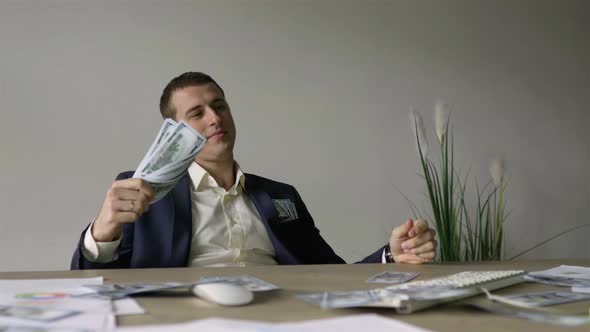 a rich guy sitting in front of a computer fanning himself with money