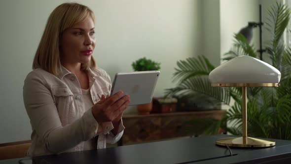 Portrait of a Pleasant Middle-aged Woman with Light Hair, She Is in the Office and Sits at a Table