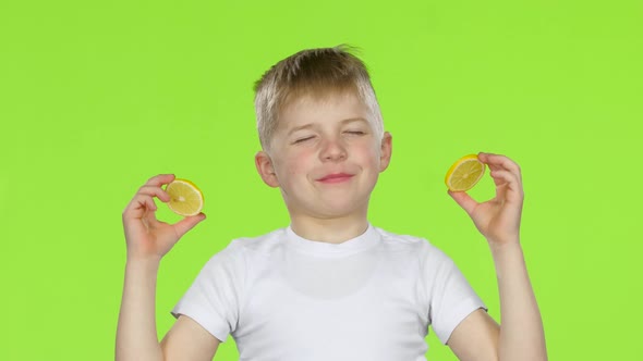 Children with Slices of Lemon Licks Them and Shows Grimaces. Green Screen