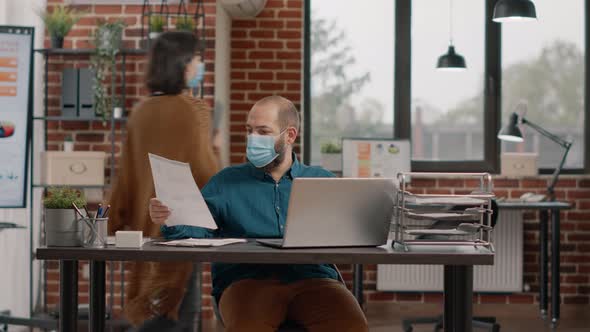 Business Man Wearing Face Mask and Looking at Documents