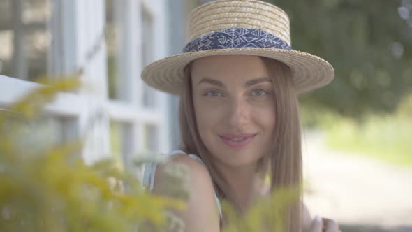 Close-up Face of Cute Young Woman in Straw Hat Looking at the Camera Smiling Happily Outdoors