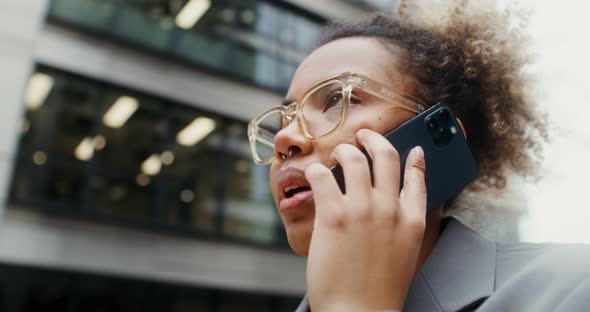 A Woman Using Mobile Phone While Standing Near an Office Building