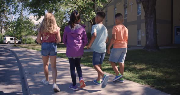 Diverse group of friends walking in front of school