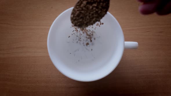 Granules of Instant Coffee are Poured Into a White Cup