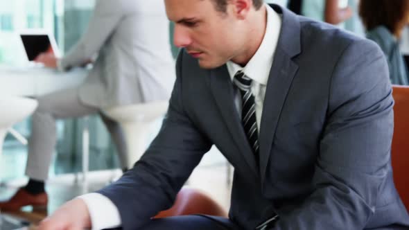 Businessman picking up a call while working in laptop