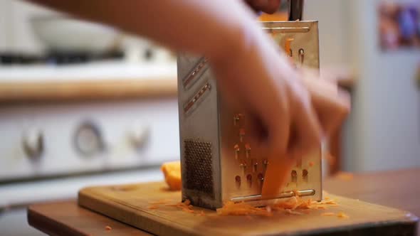 Woman Hands Rubbing Carrots on Grater in a Home Kitchen. Slow Motion