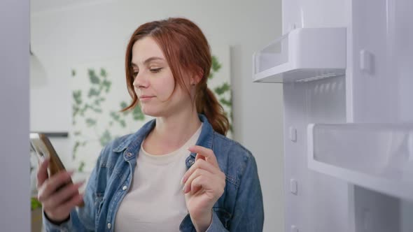 Delivery Concept, Housewife Opens an Empty Fridge Looking for Meal and Uses Modern Online Grocery