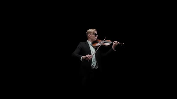 Young Caucasian Male in Black Suit and Glasses Plays Violin on Dark Background